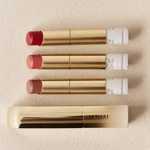 Lipstick Holder Gold next to three shades of Moisture Intense Lipstick (Refill) on neutral surface